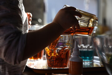 Creativity and fun of little child with colored water and pouring colored water with dye. Artistic acivity and play in kirdengarten. Chilhood and hands of kid. Closeup.