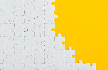 Unfinished white puzzle pieces on yellow background