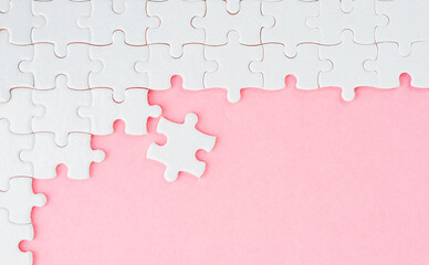 Unfinished white puzzle pieces on pink background