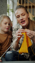 The child watches how the mother knits with knitting needles