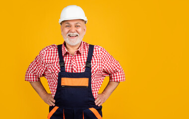 cheerful senior man builder in hard hat on yellow background