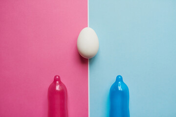 Take your pick. Studio shot of a pink and blue condom placed next to an egg against a pink and blue background.