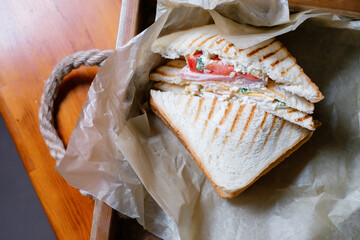 Sandwich with ham and vegetables on parchment paper. Delicious lunch close-up.