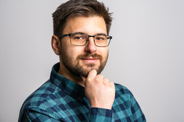 Obraz premium Portrait of one adult caucasian man 30 years old with beard and eyeglasses looking to the camera in front of white wall background smiling wearing casual shirt copy space