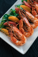 Grilled tiger prawns or shrimps with orange grapefruit and greens on a plate
