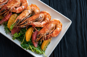 Grilled tiger prawns or shrimps with orange grapefruit and greens on a plate