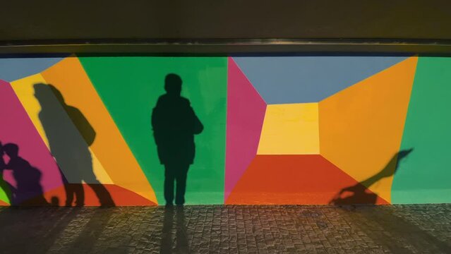 Zug, Switzerland - December 31, 2021: Silhouettes of walking people on the colorful wall along the promenade by the lake in Zug, Switzerland