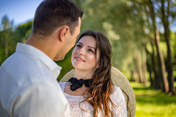 Fototapeta premium Happy young people in wedding dresses stand in the meadow and look at each other. portrait of a bride looking at her lover