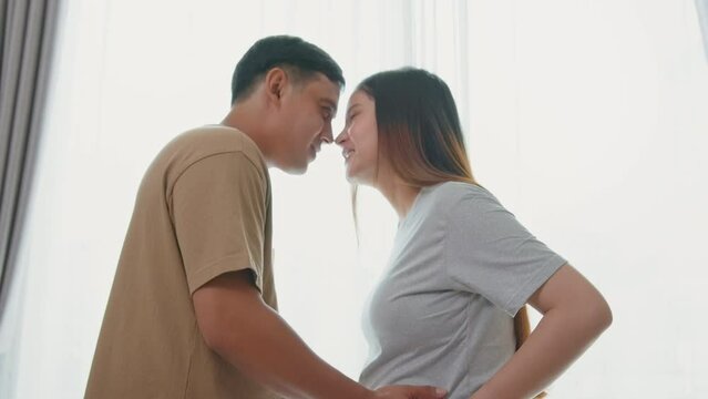 Young pregnant woman with husband embracing and expecting a baby at home