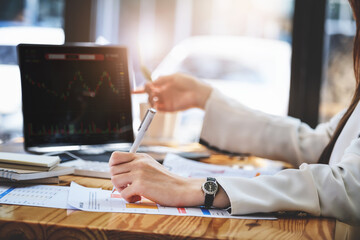 Concept of stock market analysis, financial statements, investments, Asian women entrepreneurs are using documents and computers to manage funds efficiently by working through internet technology.