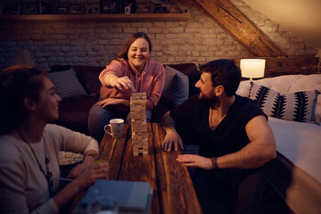 Happy roommates have fun while playing jenga game at home.