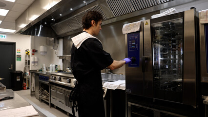 Professional chef in the kitchen of a restaurant. A male chef in a black uniform is working in the kitchen. Slow motion 4K