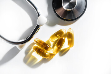 Omega 3 capsules and a stethoscope on a white background with copy space.
