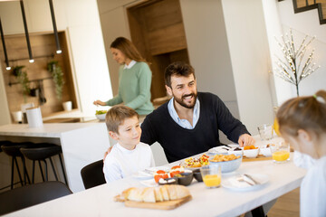 Young happy family talking while having breakfast at dining table