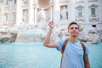 Young man near fountain Fontana di Trevi with coins in hands - 495971080
