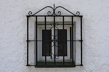 An old window covered by an ornate metal grill in the backstreets of the Spanish town of Estepona on the Costa del Sol - obrazy, fototapety, plakaty