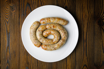 meat products on a white plate on a wooden table
