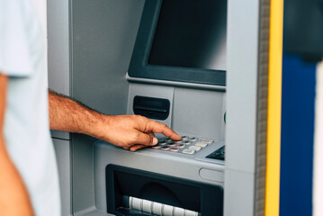 Close up of man hand withdrawing money at automatic atm machine typing secret security code number. Concept of banking activity and business work. People and bank outdoor atm