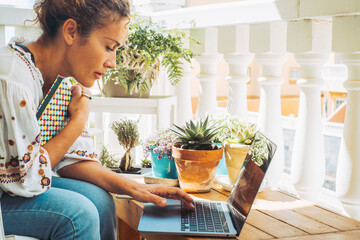 Side portrait of serious business woman working from home in outdoor terrace using laptop. People...