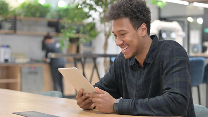 Successful African American Man Celebrating on Tablet at Work 