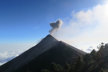 Panorama scene from the breathless Acatenango Volcano in Guatemala in Central America erupting with smoke and lava on a sunny day with a blue sky 