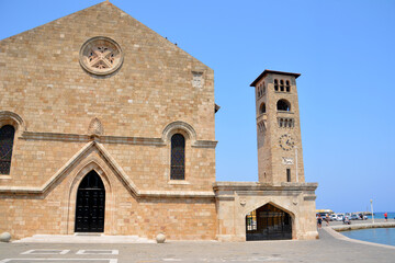 brick square with ancient church and tower with clock in Rhodes, Greece