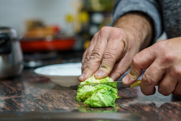 Male hands chopping up a lettuce in the kitchen.