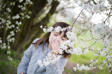 dziewczynka zachwycona wiosną podziwia i wącha kwiaty - obrazy, fototapety, plakaty