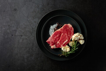 Raw beef meat steak with rosemary, garlic, salt, and pepper.
