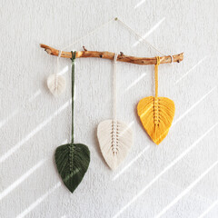 Macrame leaves wall hanging in yellow, white and green  and natural color on the wooden stick. Cotton rope decor macrameto make your room more cozy and unique. Copy space