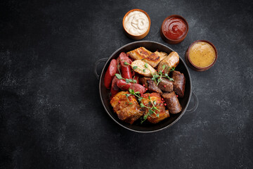 Grilled meat platter in a pan and sauces