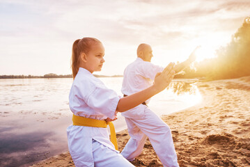 Sensei and her young female student are training on the sand, against the backdrop of the river and...
