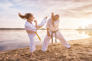 Sensei and her young female student are training on the sand, against the backdrop of the river and...
