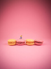 Macaroons in pastel colors, on a turquoise mint background. Roller skater riding on a french colorful macaroons, conceptual photography.