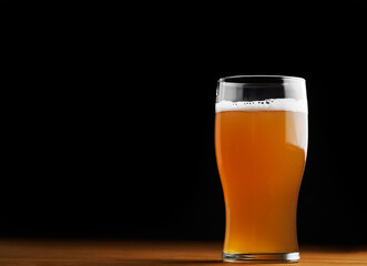 glass of beer on a wooden table, black background