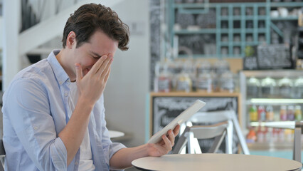 Creative Man Reacting to Loss on Tablet in Cafe 