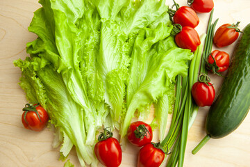 Salad leaves and tomatoes and green onion and cucumber, top view. Background from fresh vegetable for salad. Raw green and red vegetables for poster, screensaver, wallpaper, postcard, cover, website