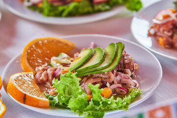 Traditionally made Mexican ceviche. Fish strips with tomato, lettuce, onion, avocado, orange.
