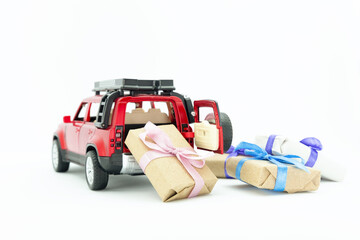 Fototapeta premium red toy car delivering gift boxex present on white background copy space