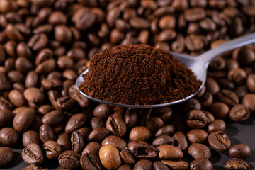 a spoonful of ground coffee on a background of beans
