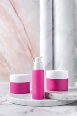 Pink cosmetic jars with white lid on marble background. Mockup. Face cream and serum bottle blank labels for branding.