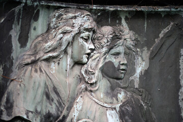 An old, and extremely weathered sandstone relief which shows an elder sister who reassuring her younger sister.