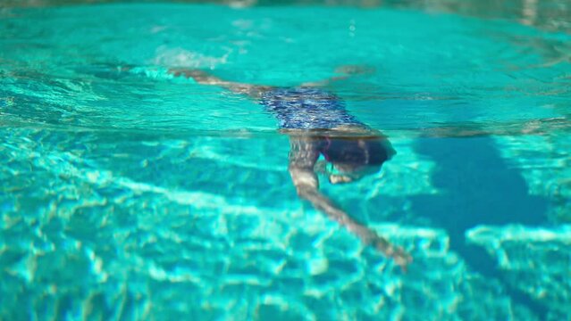 Happy girl dives under the water in swimming pool. Vacations concept.