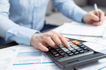 Man with bills and calculator. Businessman using calculator to calculate bills at the table in office. Financial accounting concept