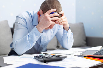 Distressed young man sit at desk paying bills feel stressed having financial problems. Unhappy...