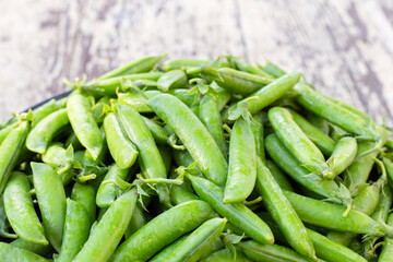 Bunch of freshly picked pea pods on wooden table background