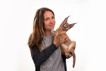 young girl holds a caracal kitten in her hands on a white isolated background - 495983446