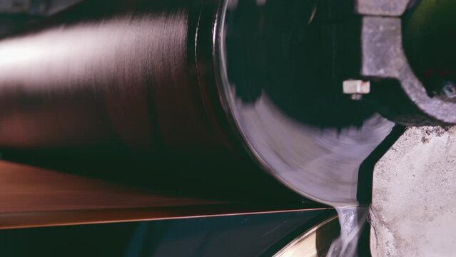 cardboard factory. mechanical rollers remove moisture from the paper. the factory machine is set in motion to carry out the function of producing cardboard paper