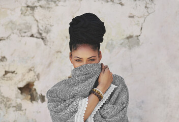 Beauty attracts the eye but personality attracts the heart. Cropped portrait of an attractive young woman covering her mouth with her poncho.