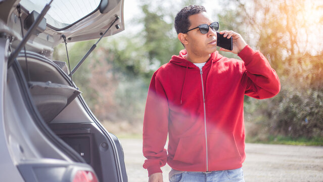 handsome young Hispanic crashed with his car using his cell phone. road safety concept